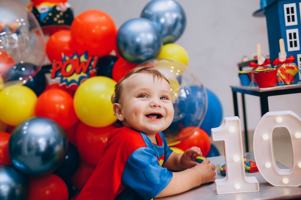 A smiling child at a colorful superhero themed birthday celebration with balloons and decorations Roanoke, Va.