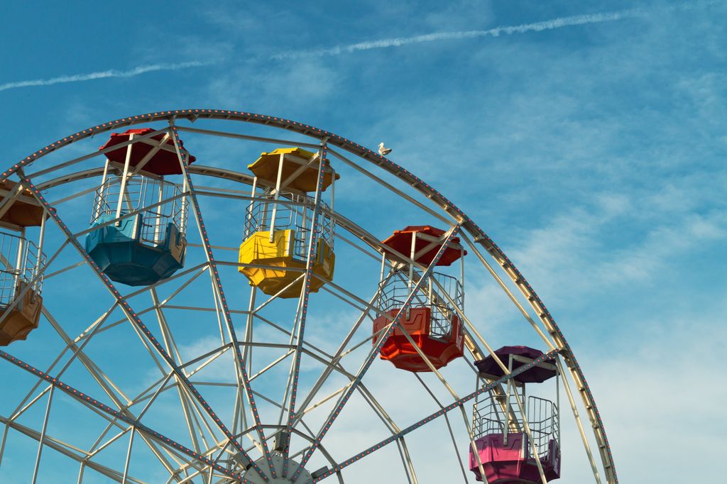 Brightly colored Ferris wheel cabins in front of a clear blue sky at a fairground, capturing a fun atmosphere.