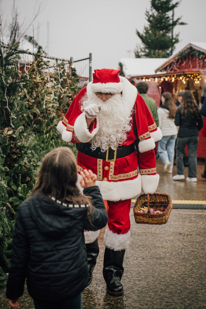 Santa Claus interacts with visitors at a festive Christmas market.