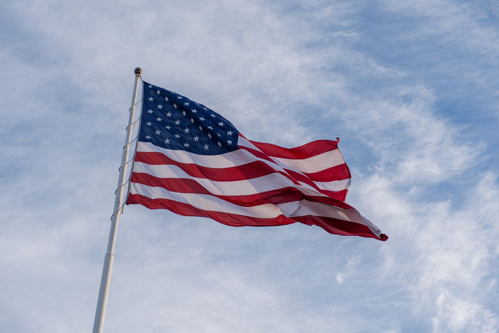 The American flag waves proudly against a backdrop of blue sky, symbolizing freedom and patriotism.