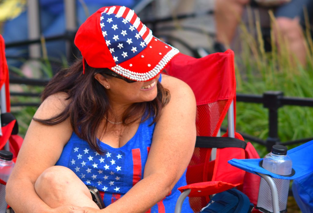 Woman wears American flag-themed attire outdoors, enjoying the event.