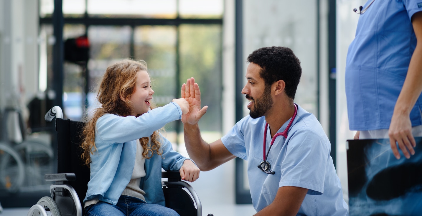 child in wheelchaior fist bumps nurse in the hospital